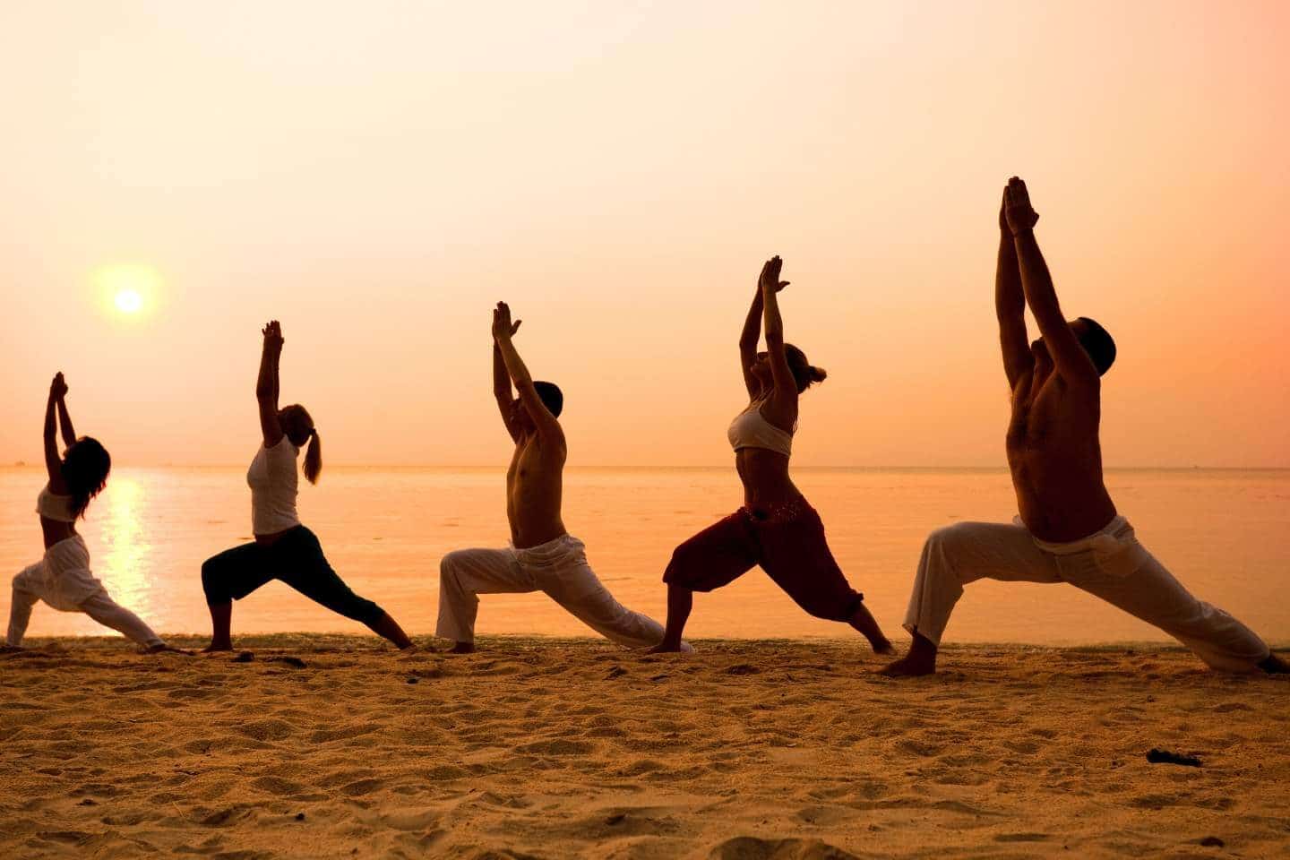 Group of people practicing yoga on the beach